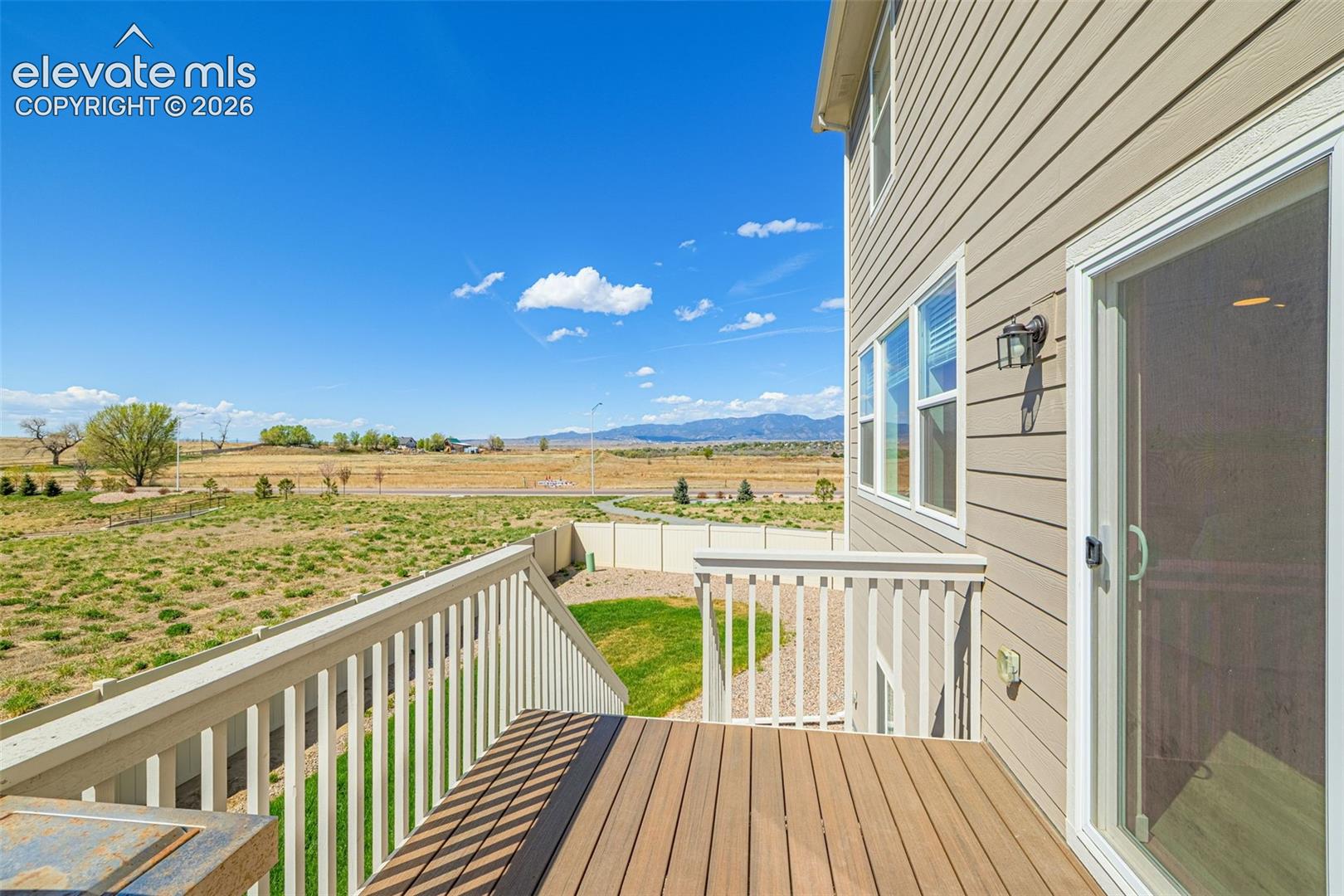 Composite wood-finish decking, white railings, and a sliding glass door