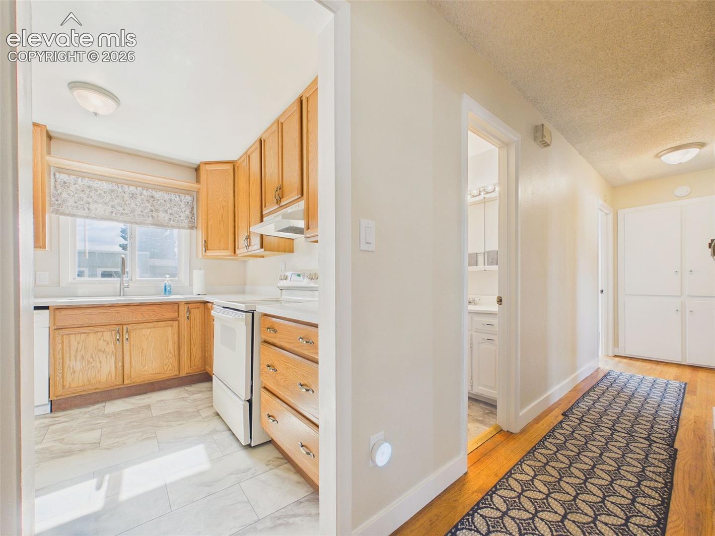 Convenient hallway connecting the kitchen, bathroom, and bedrooms, featuring hardwood flooring and additional built-in storage.