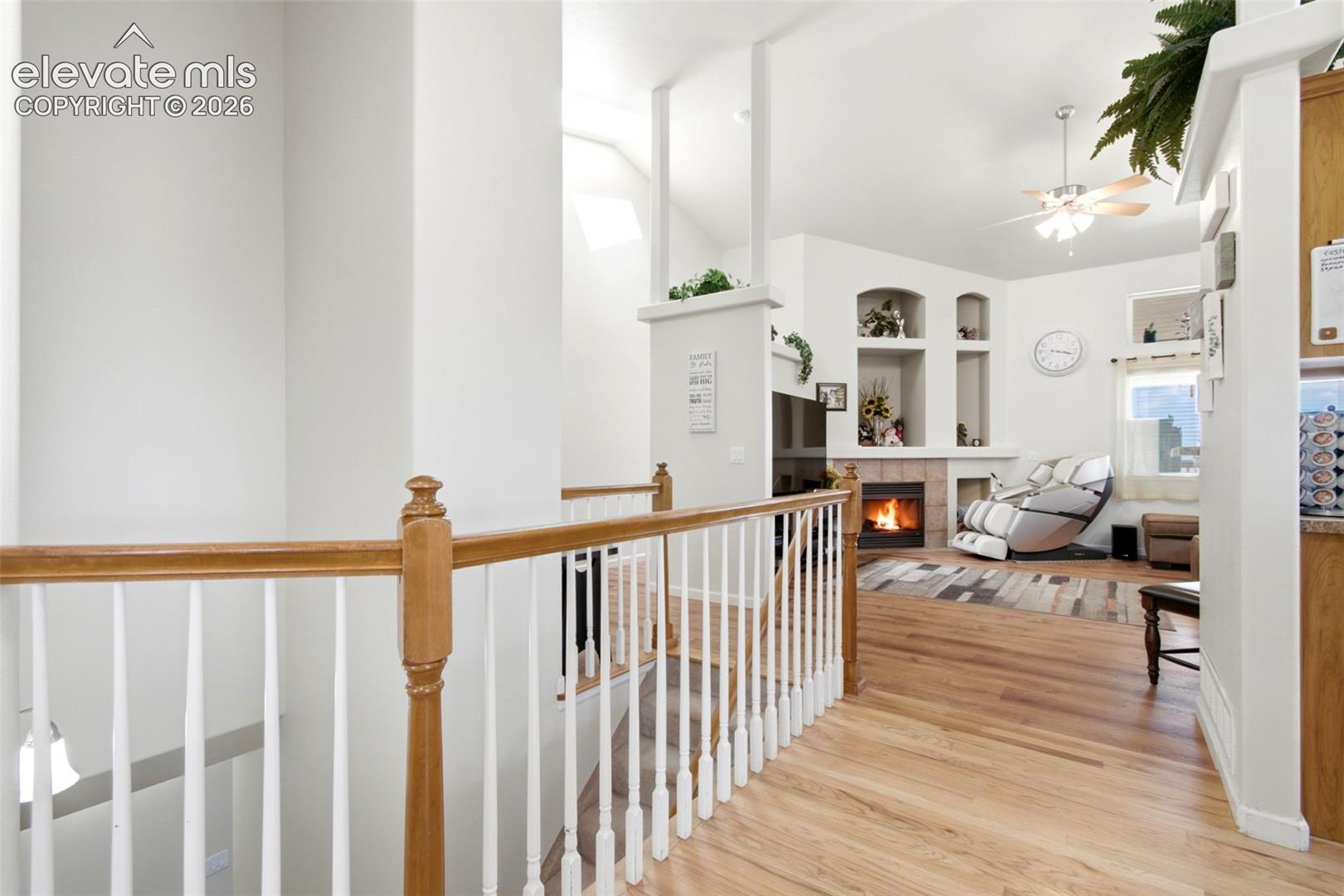 Hallway featuring a vaulted ceiling, built-in fireplace, recessed shelving, and a ceiling fan