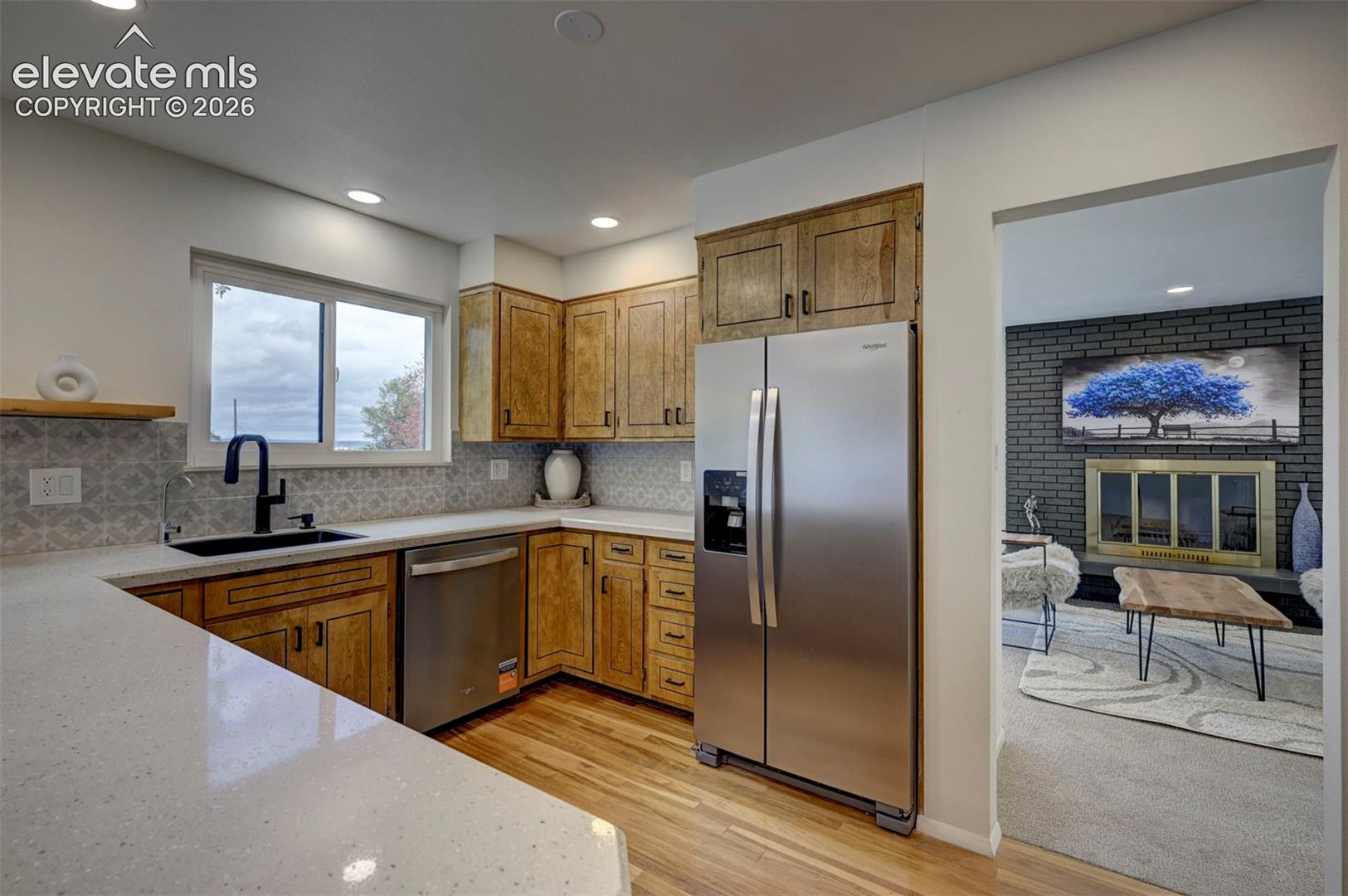 Kitchen featuring wood cabinetry, solid-surface countertops, stainless steel appliances, a matte black faucet, and patterned backsplash tile