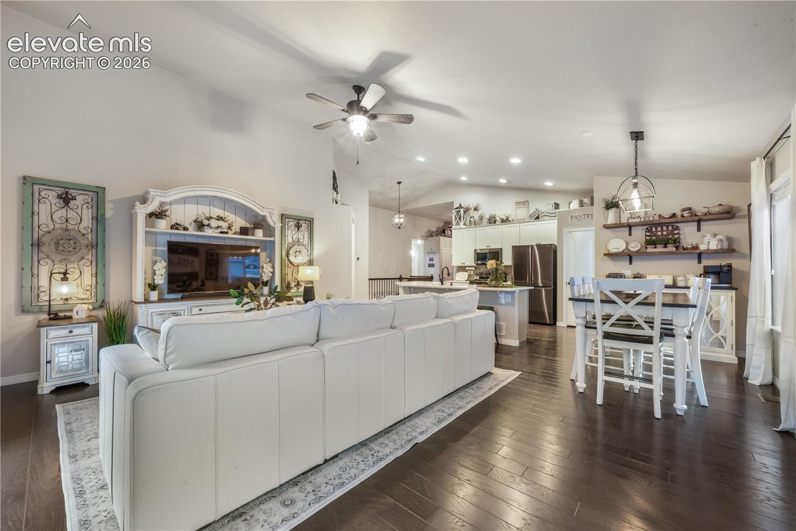 Vaulted ceilings, wood-finish flooring, recessed lighting, and a ceiling fan