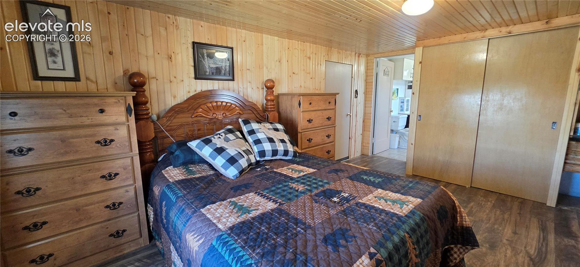 Wood-finish wall paneling, coordinating wood-finish ceiling, wood-finish flooring, and sliding closet doors