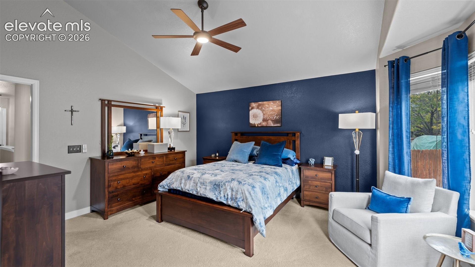 Vaulted ceiling featuring a central multi-blade light fixture and neutral wall finishes with a prominent accent wall