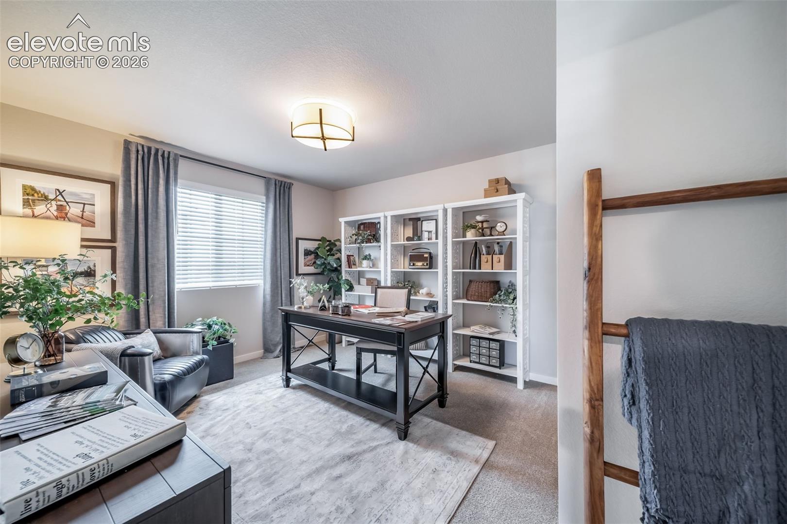 Dedicated office space featuring two built-in shelving units, a large window with blinds, overhead lighting, and carpet flooring
*Photos of a model home*