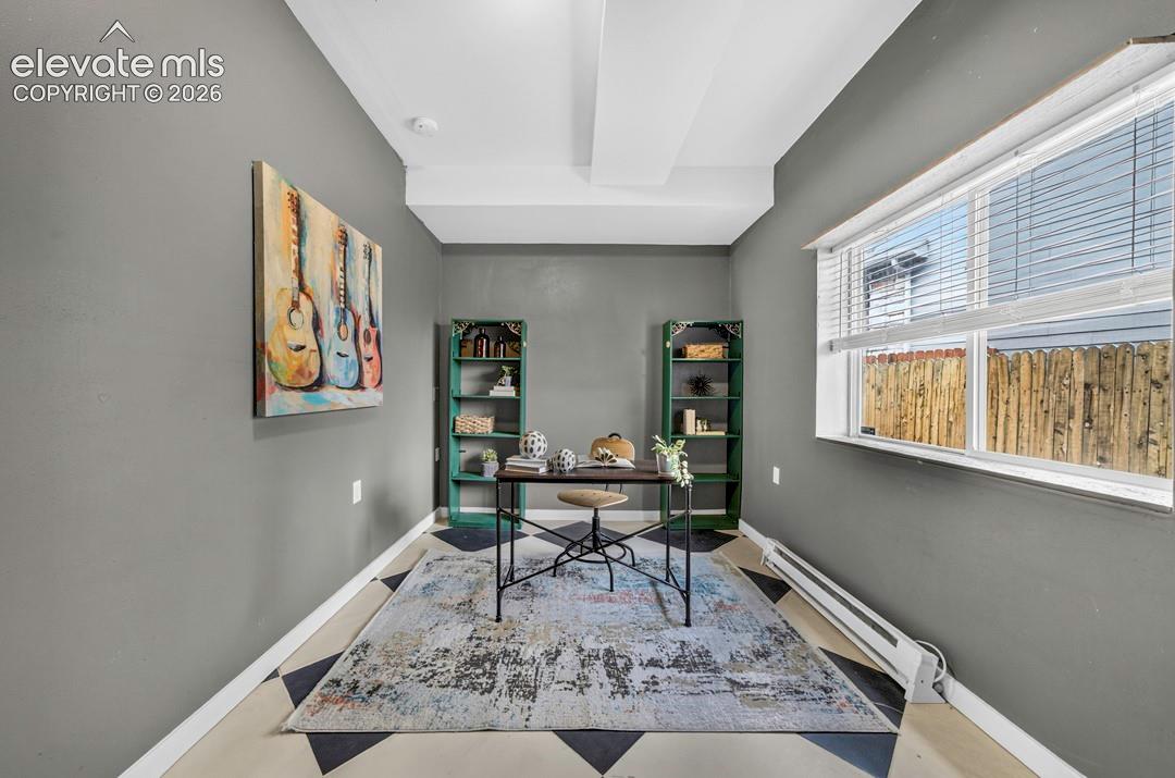 Interior room featuring grey-toned walls, geometric patterned flooring, and a large window with horizontal blinds