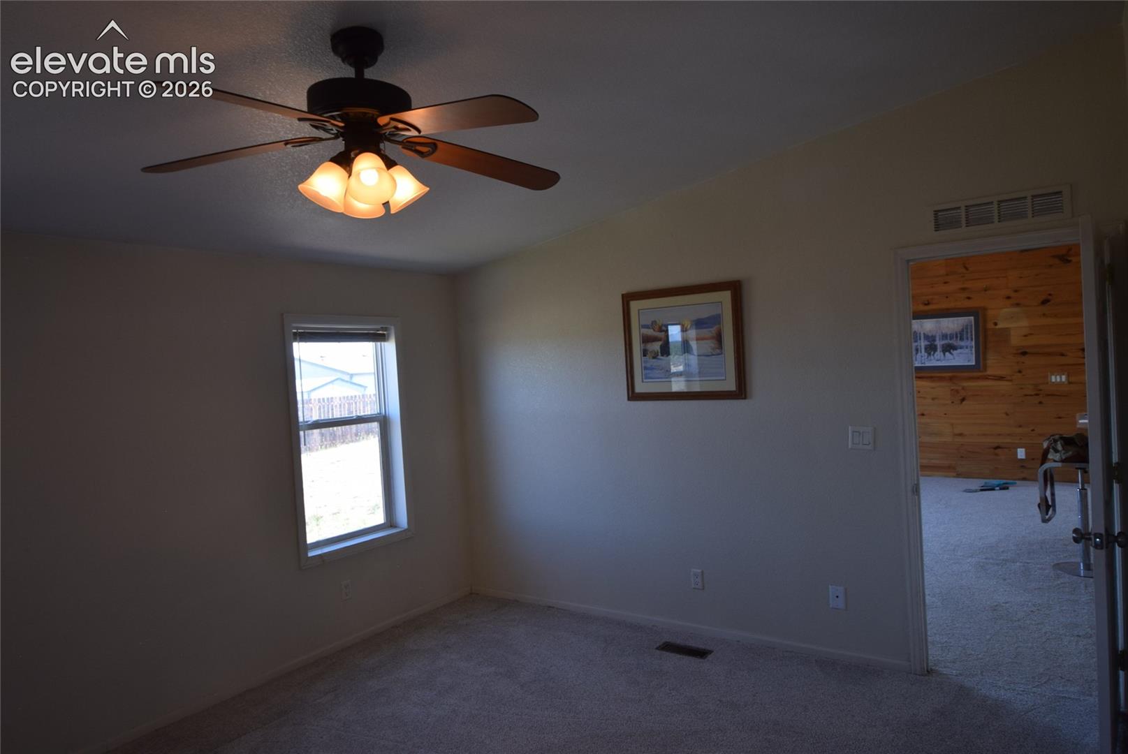 Vaulted ceiling with a ceiling fan and integrated lighting, single window, and neutral-toned wall paint