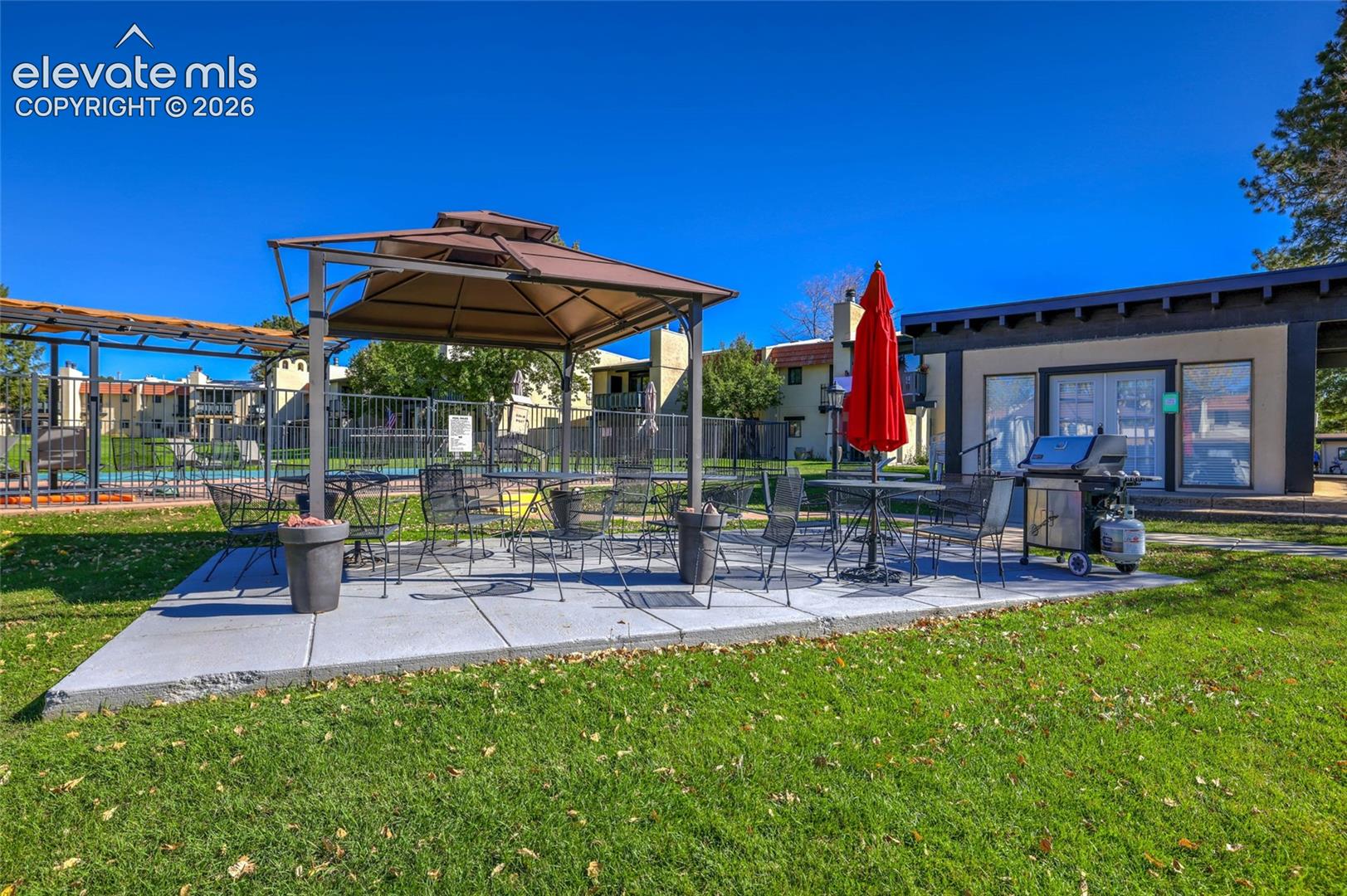 community outdoor patio area featuring a concrete paver surface, metal gazebo, and integrated fencing