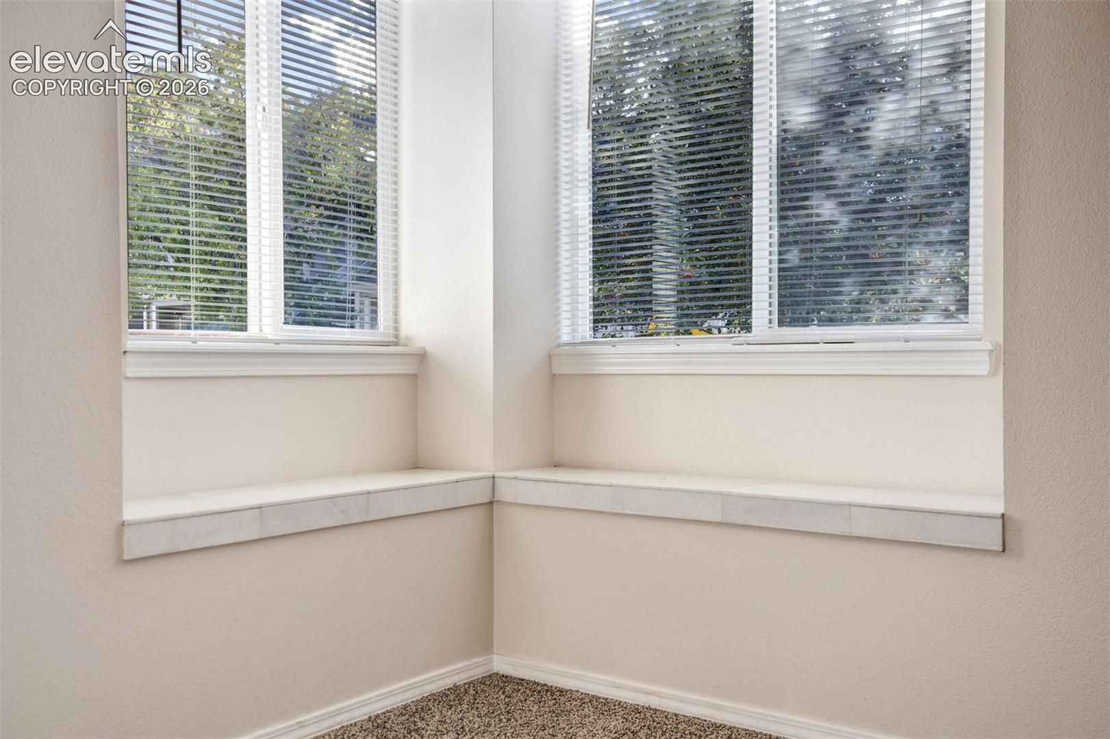 Corner alcove featuring dual windows, tile-finished ledge seating, and neutral wall color