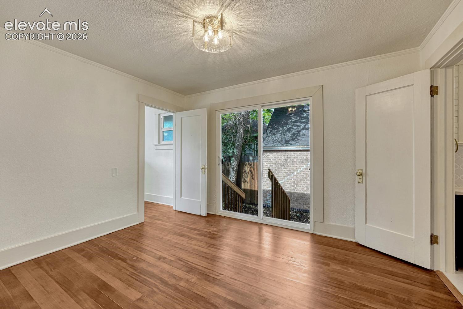 Wood-finish flooring, white trim work, ceiling-mounted light fixture, and sliding glass doors to an exterior deck