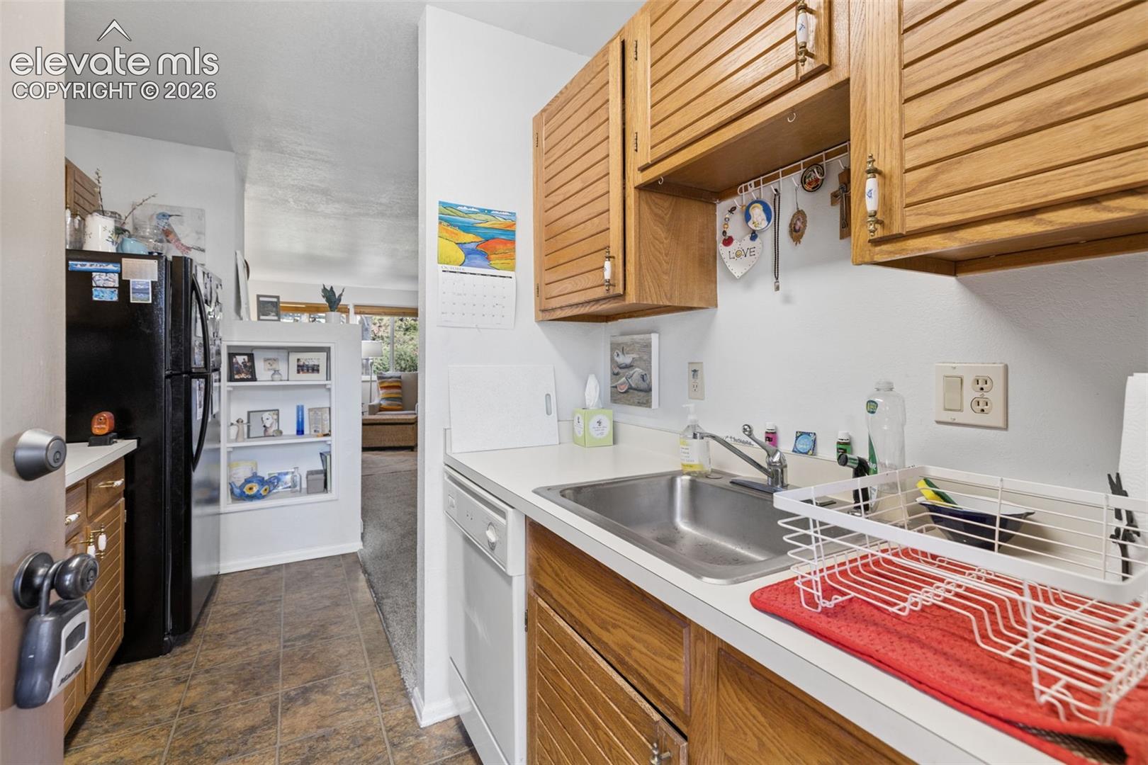 Kitchen featuring wood-finish cabinetry, white countertops, and a stainless steel sink