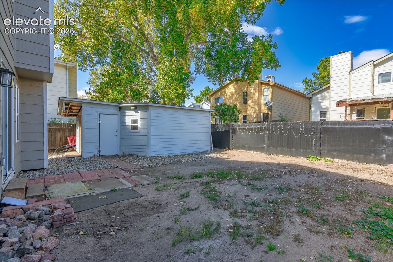 Exterior space featuring a detached storage structure, concrete masonry perimeter fencing, and a stone-lined foundation border