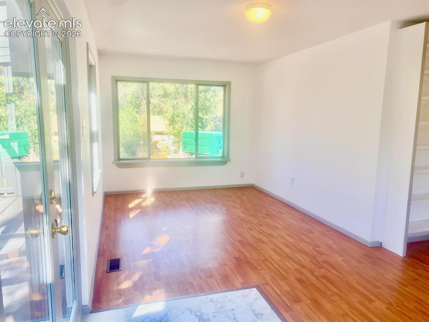 Wood-finish flooring, white walls, built-in shelving, and a glass-paneled door