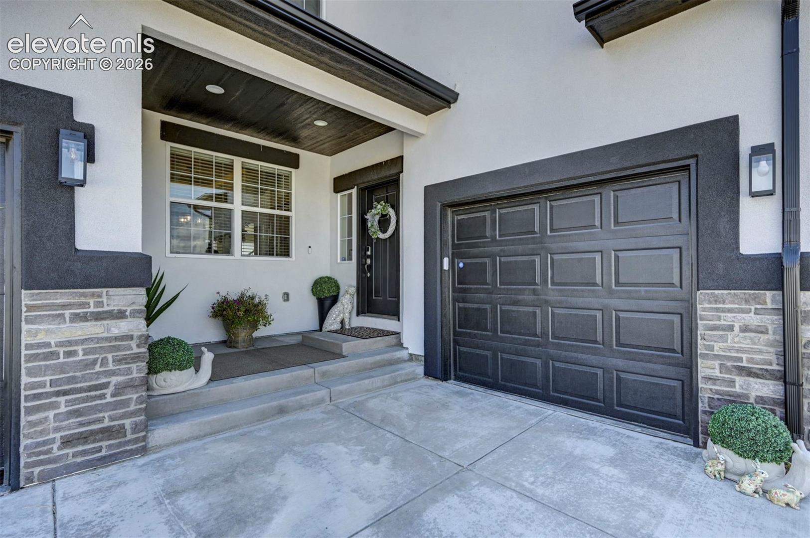 Contemporary exterior with a paneled garage door and a covered entryway