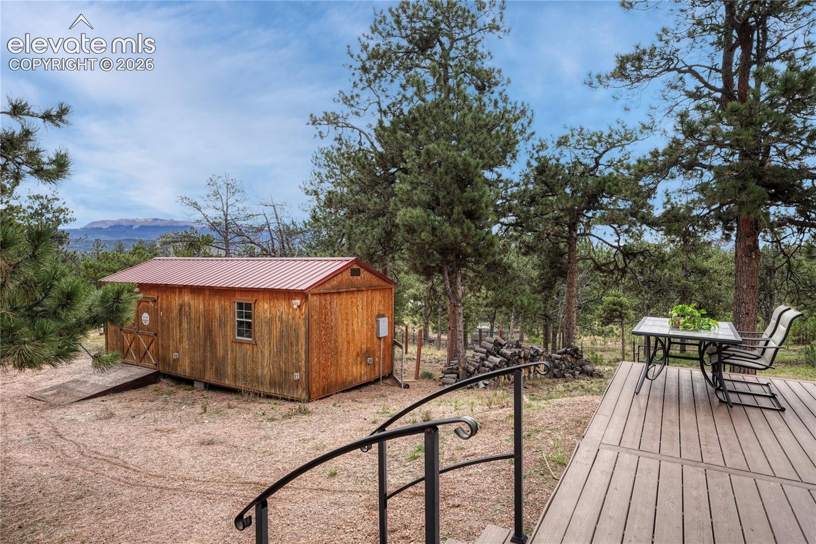 Workshop featuring a metal roof, composite decking with a black metal railing, and a mountain backdrop