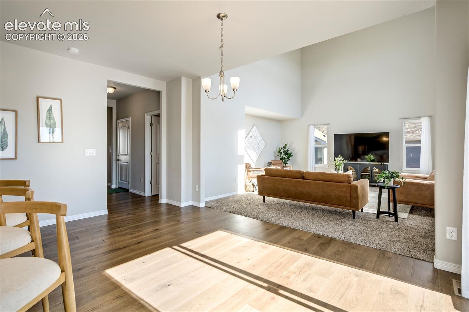 Open concept living space featuring wood-finish flooring, vaulted ceilings, and a modern chandelier