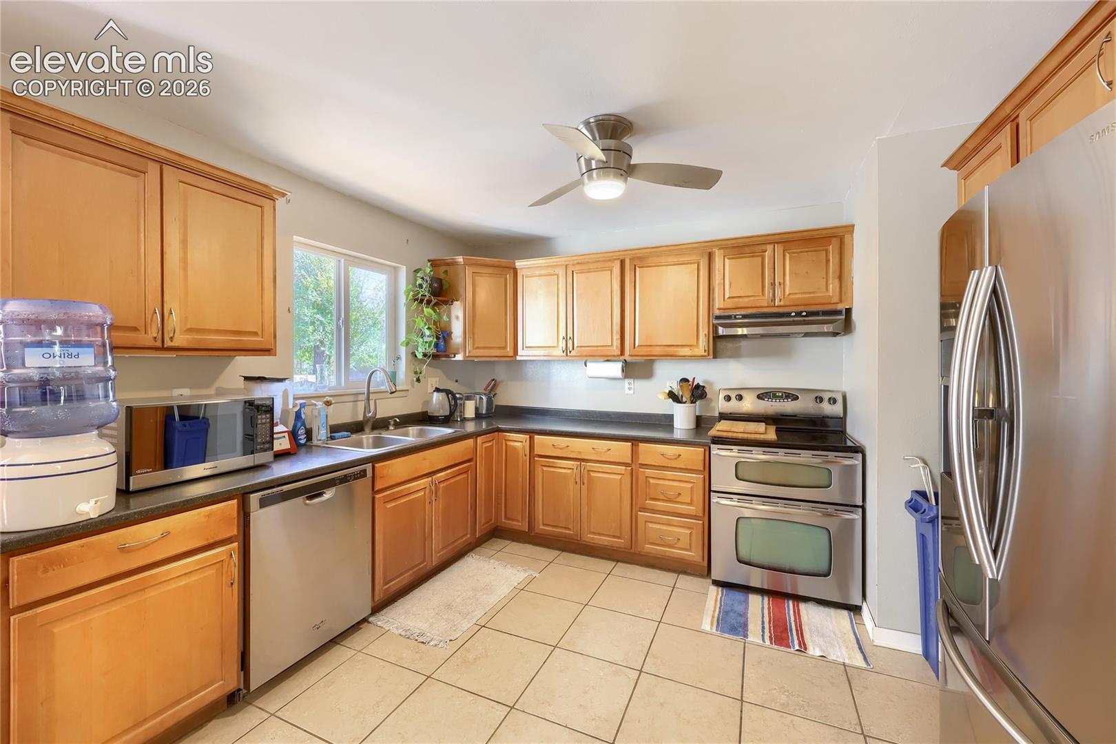 Kitchen featuring wood cabinetry, stainless steel appliances, tile flooring, and a ceiling fan