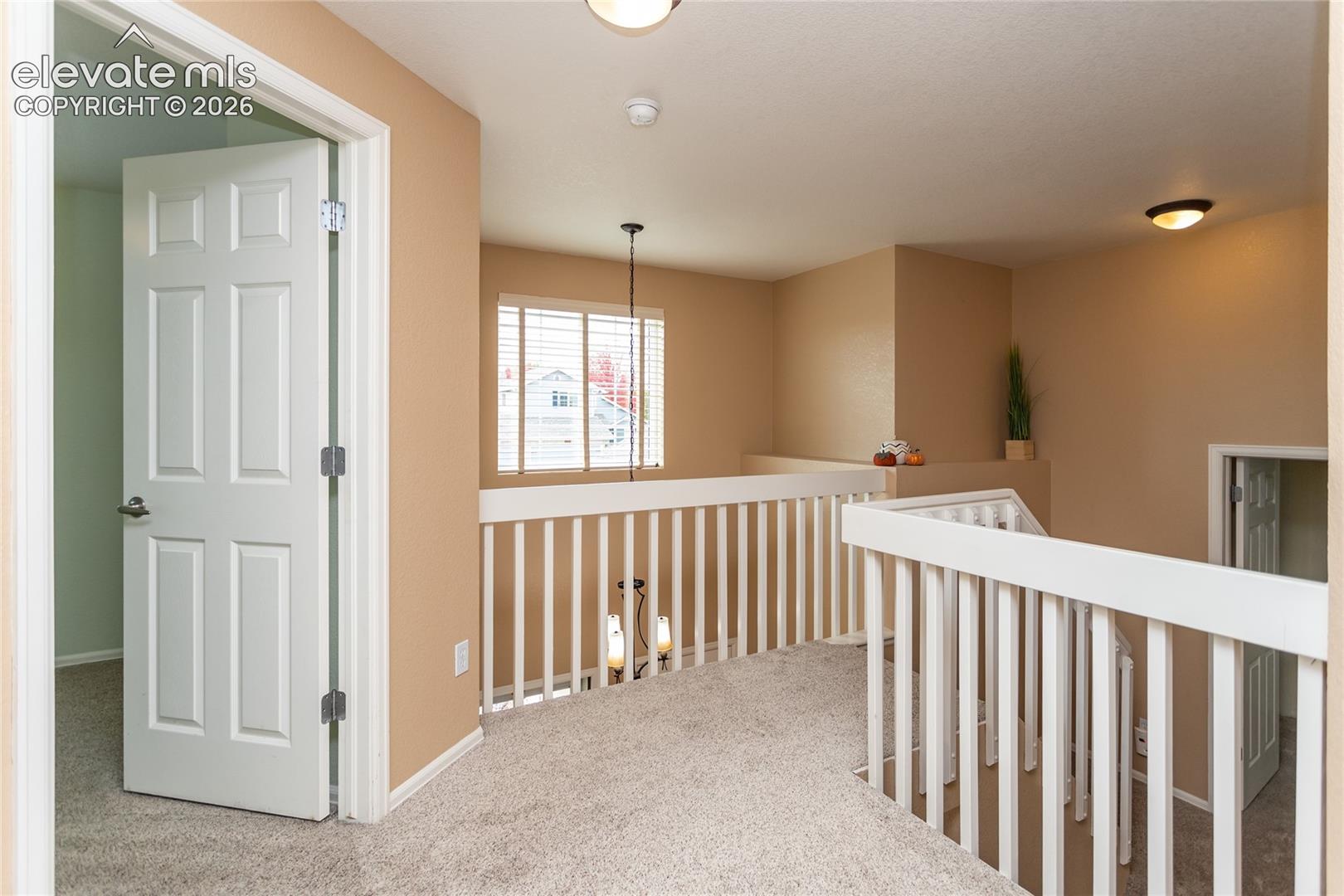Upper level hallway to 3 bedrooms and 1 full bathroom. Carpeted landing area featuring a white wooden balustrade.