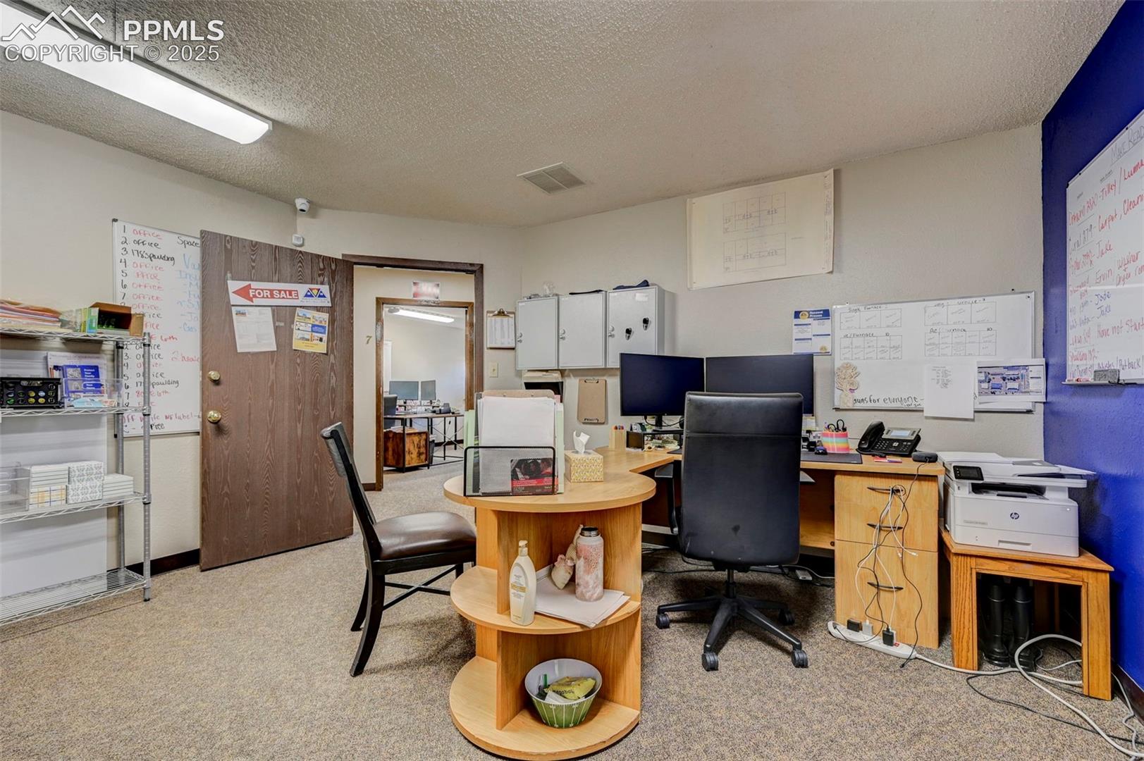 Office area with light colored carpet and a textured ceiling