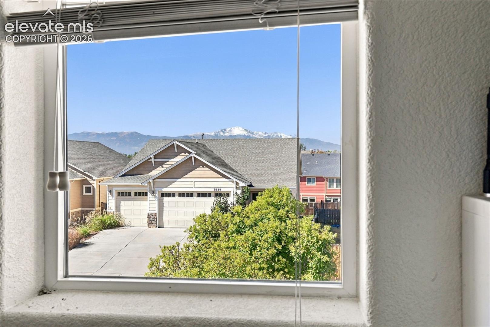 Window framing a mountain backdrop with distant snow-capped peaks