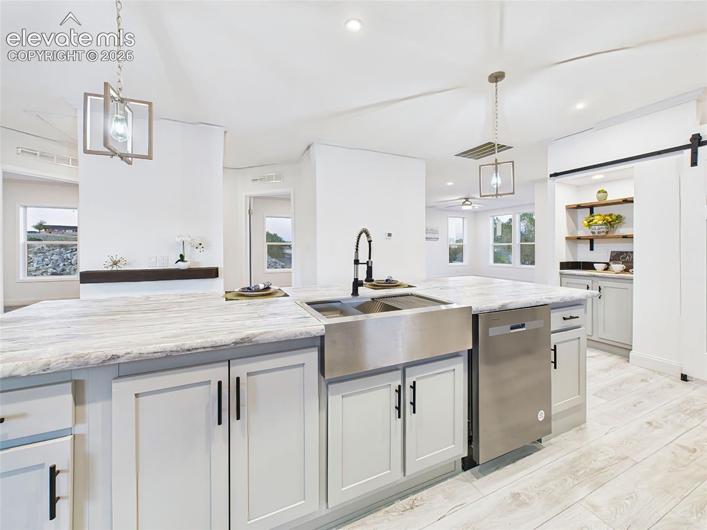 Functional island with farmhouse sink, high-arc black faucet, and integrated dishwasher—beautiful and efficient.