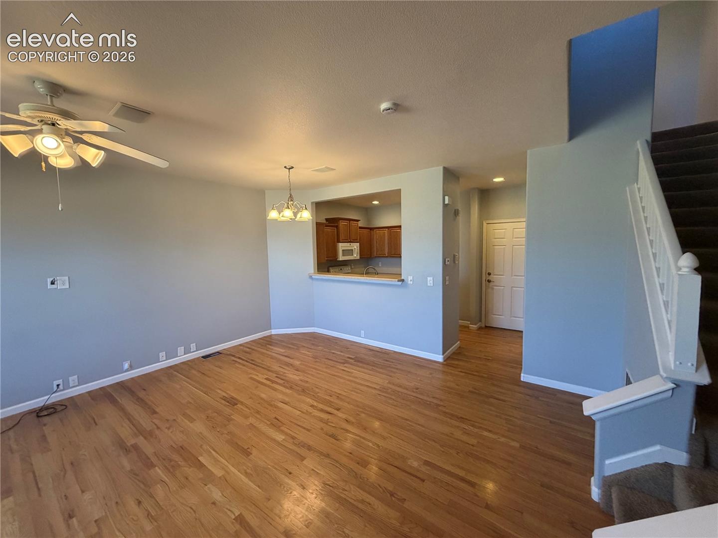 Wood-finish flooring, ceiling fan with integrated lighting, recessed lighting, white panel door, and a built-in breakfast bar