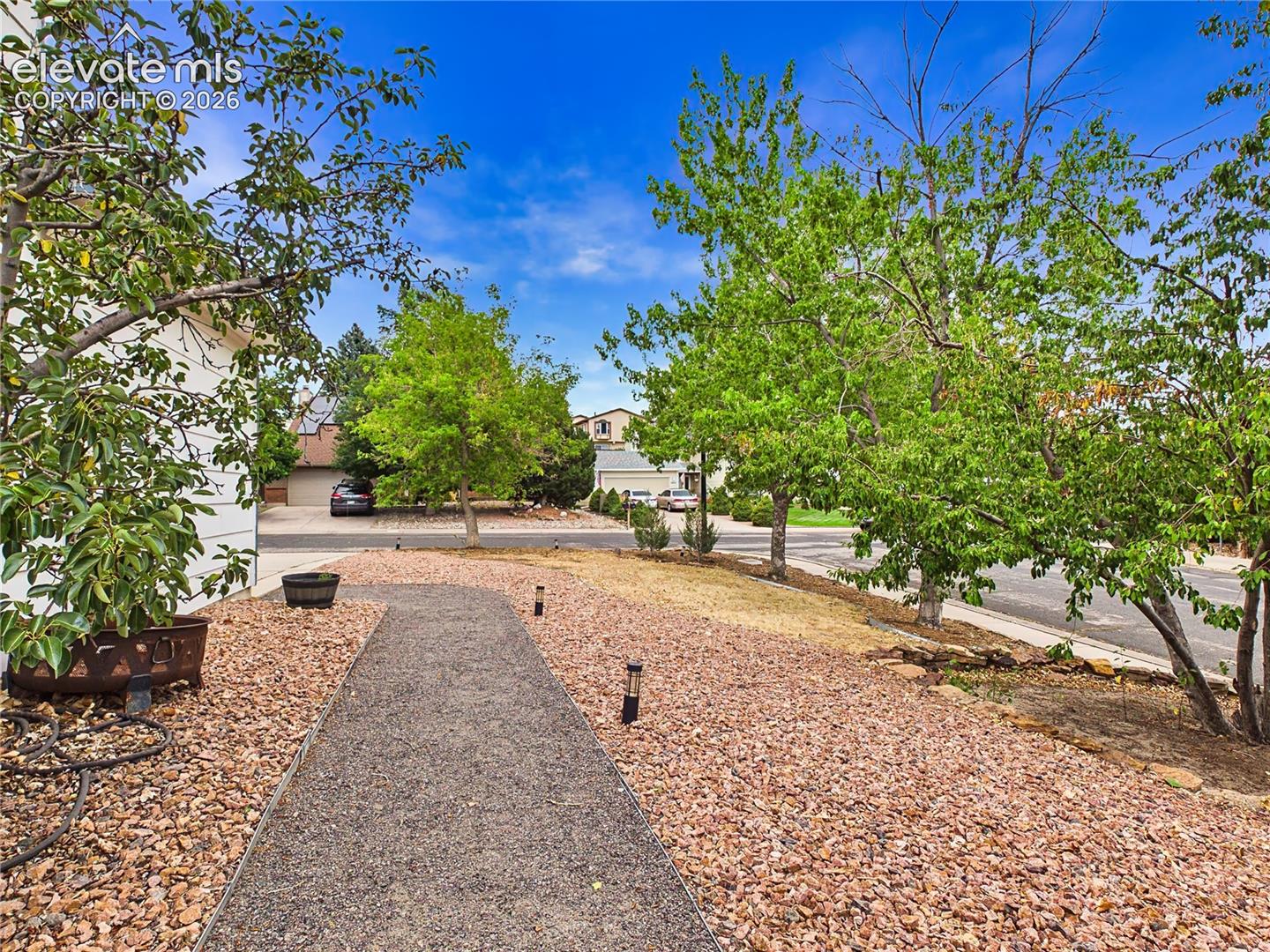 Landscaped front yard with mature trees, decorative rock, and a welcoming walkway leading to the home.