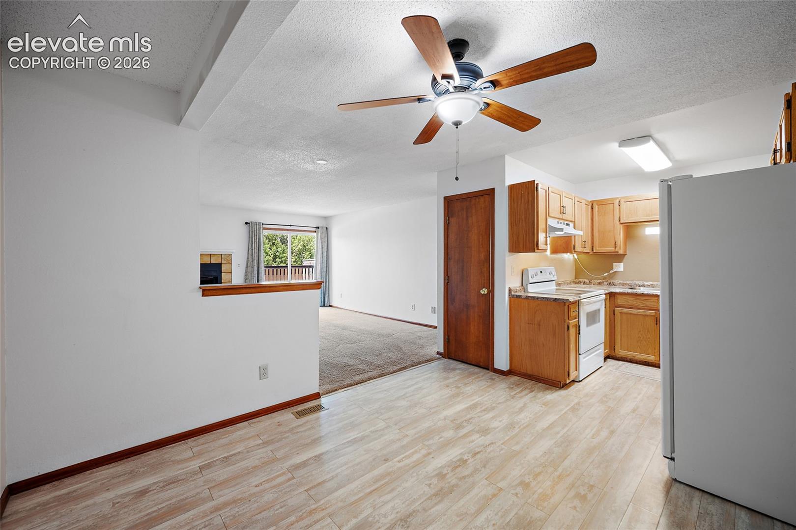 Kitchen featuring wood-finish cabinetry, white appliances, and laminate countertops