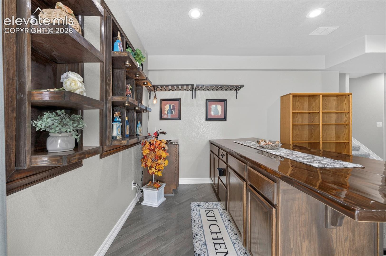 Custom built-in dark wood shelving, bar counter with a high-gloss finish, wood-finish flooring, recessed lighting, and wall-mounted storage racks