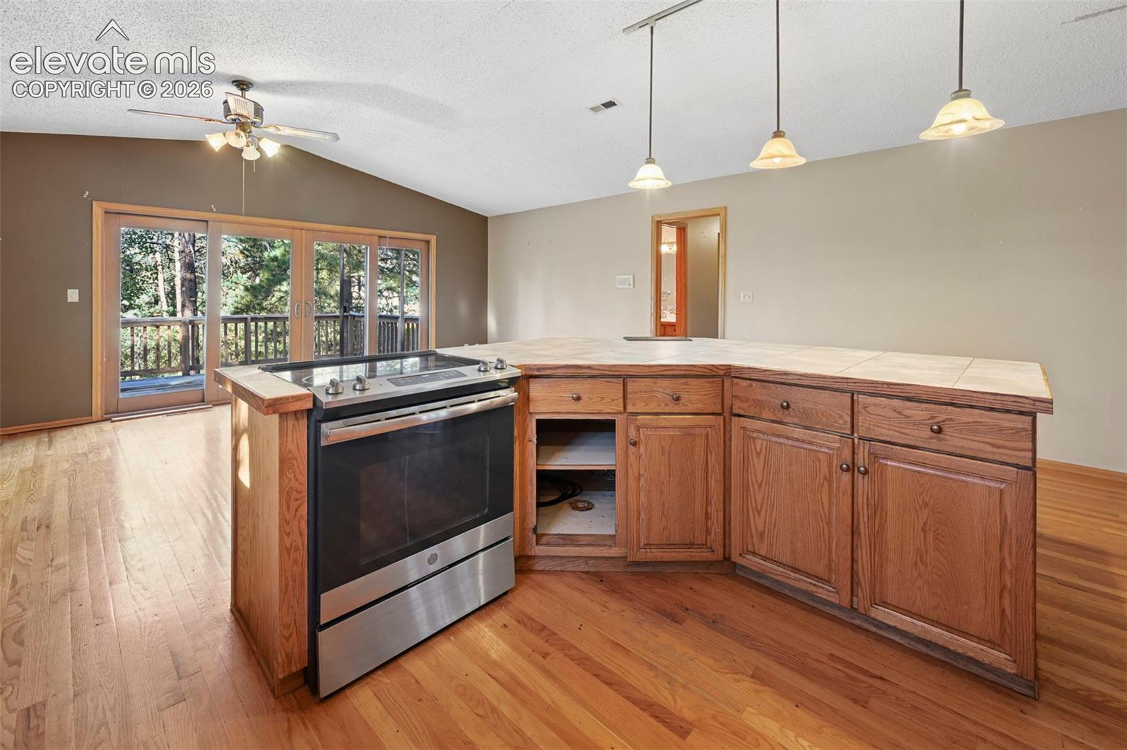 Hardwood flooring, stainless steel range, built-in cabinetry, tile countertop, and sliding glass doors