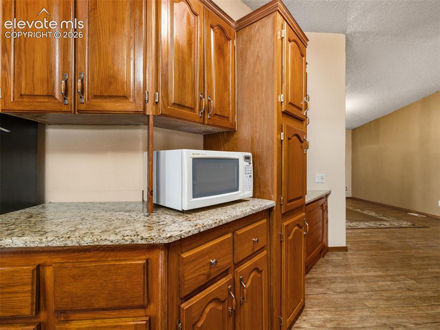 Kitchen featuring wood cabinetry, stone countertops, and wood-finish flooring