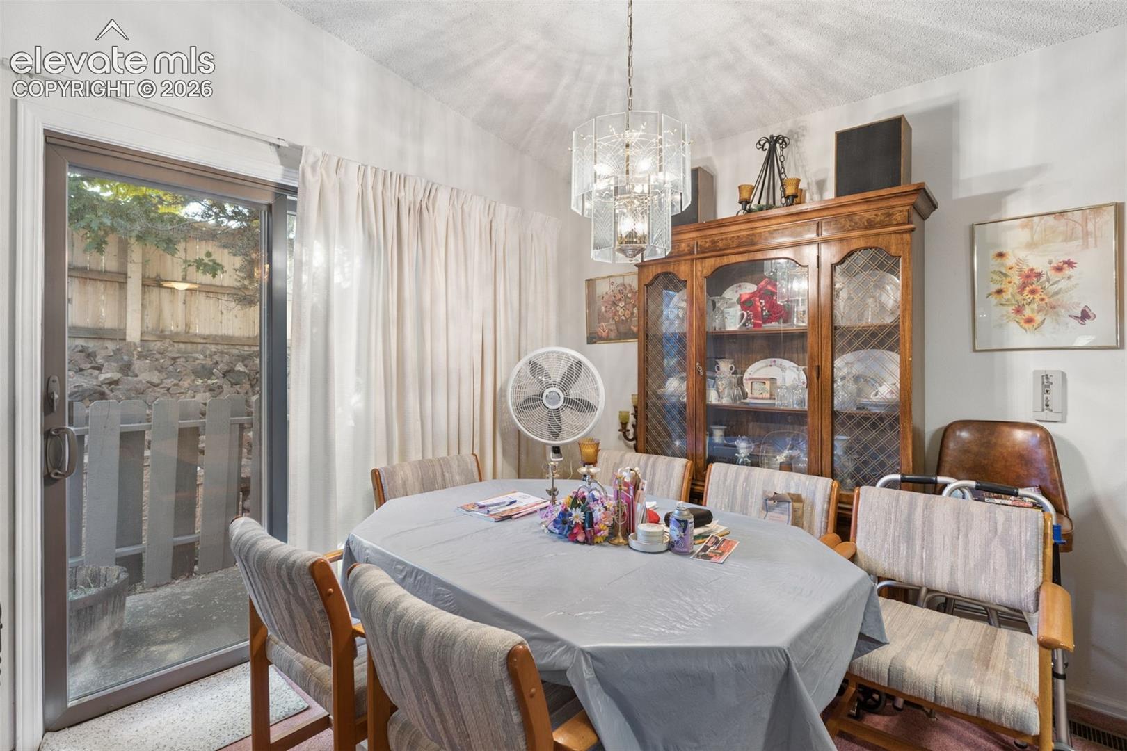 Sliding glass door, decorative tiered chandelier, and wall-mounted cabinetry