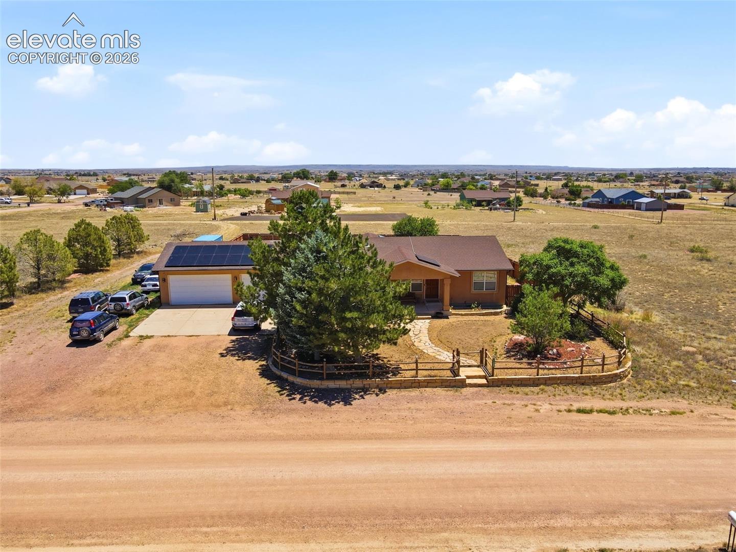Ranch-style residence featuring a prominent solar panel array, attached garage, and a winding stone pathway leading to the entry