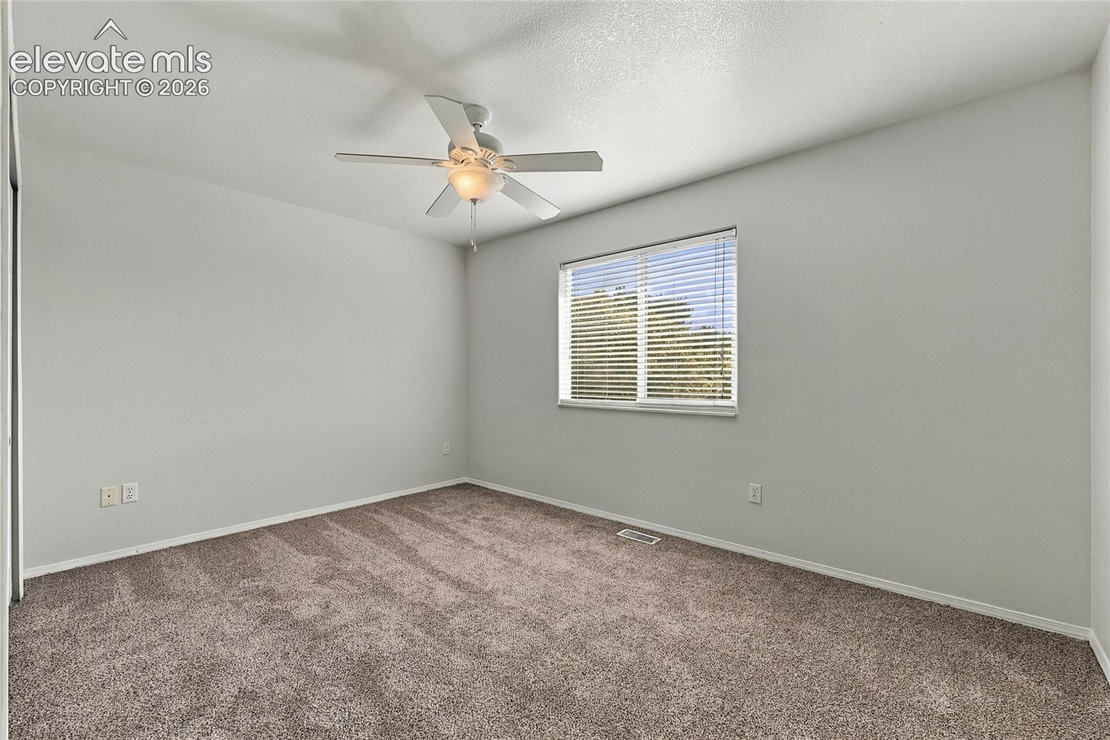 Neutral-toned walls, plush wall-to-wall carpeting, ceiling fan with integrated light fixture, and window featuring horizontal blinds