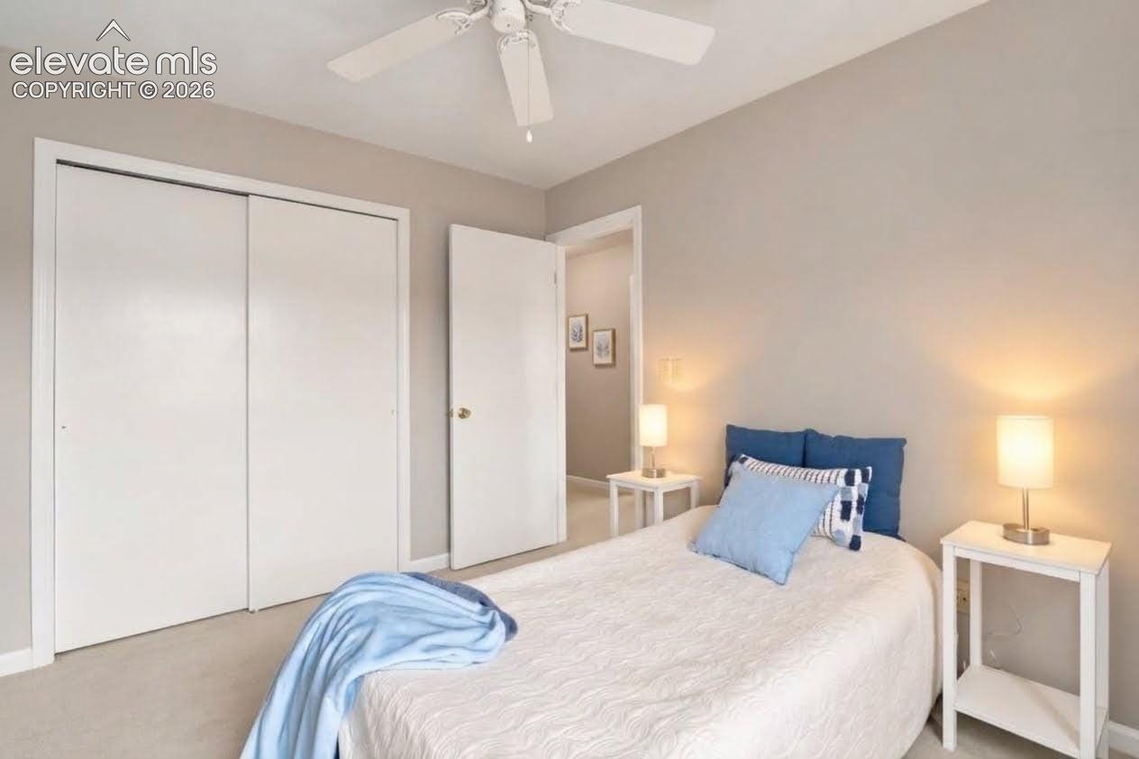 Room featuring neutral wall paint, white sliding-door closet, wall-to-wall carpeting, and a ceiling fan with integrated lighting