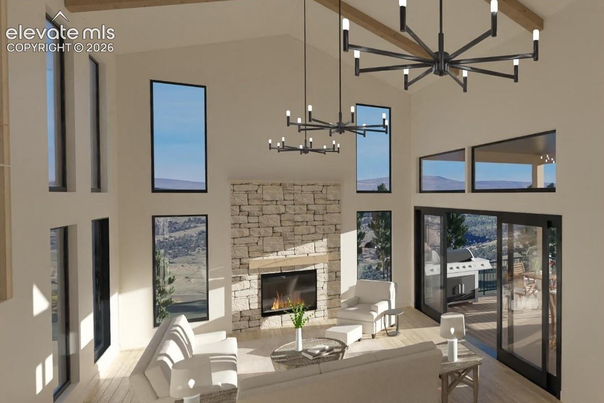 Vaulted ceiling with exposed wood beams, stone-clad fireplace with wood mantel, multiple large windows, sliding glass door, and wood-finish flooring
