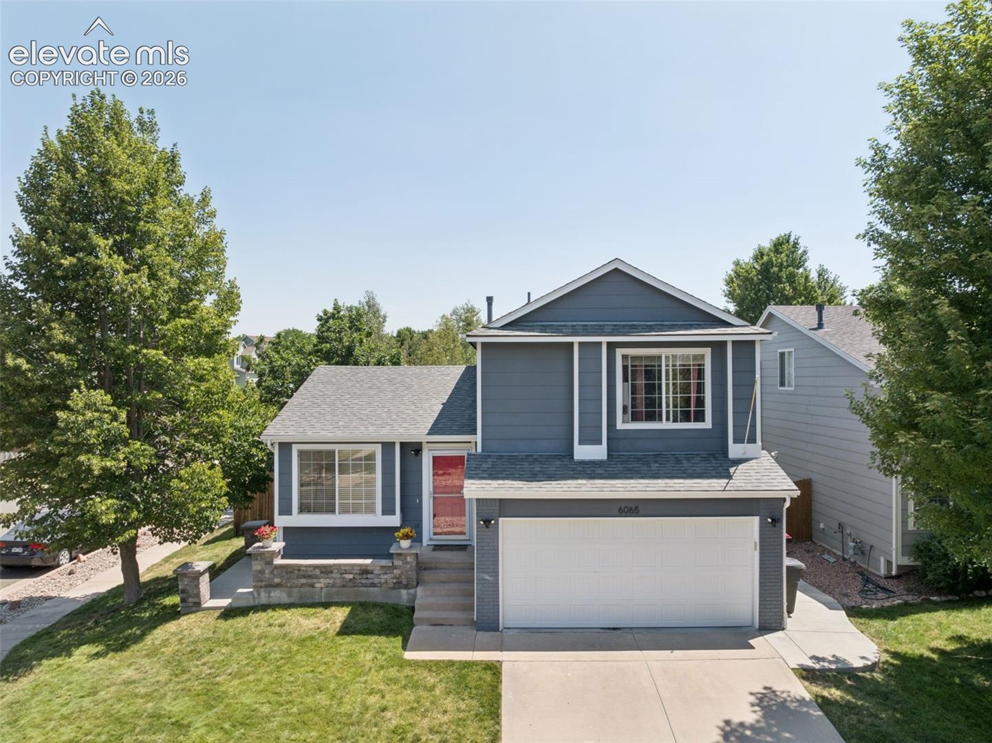 Two-story home with a two-car garage, gray siding, and a red entry door