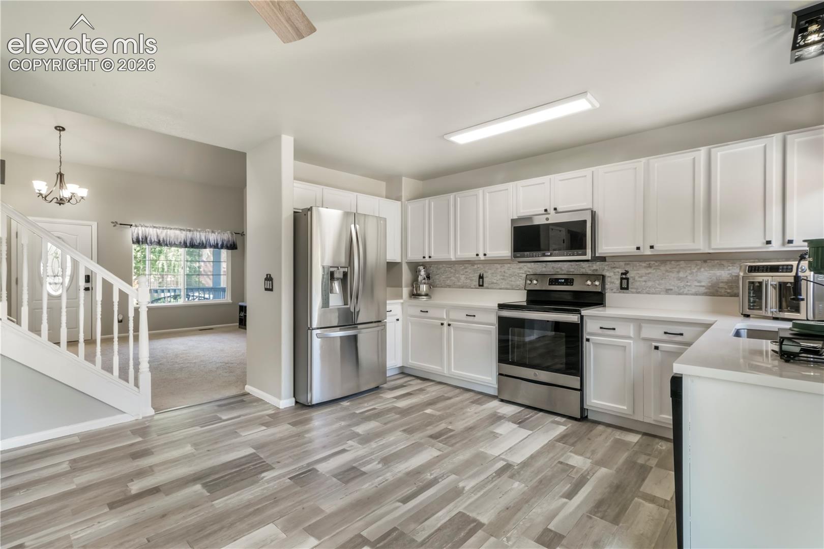 Kitchen with new LVP floors, stainless steel appliances and abundant cabinets and access out to patio