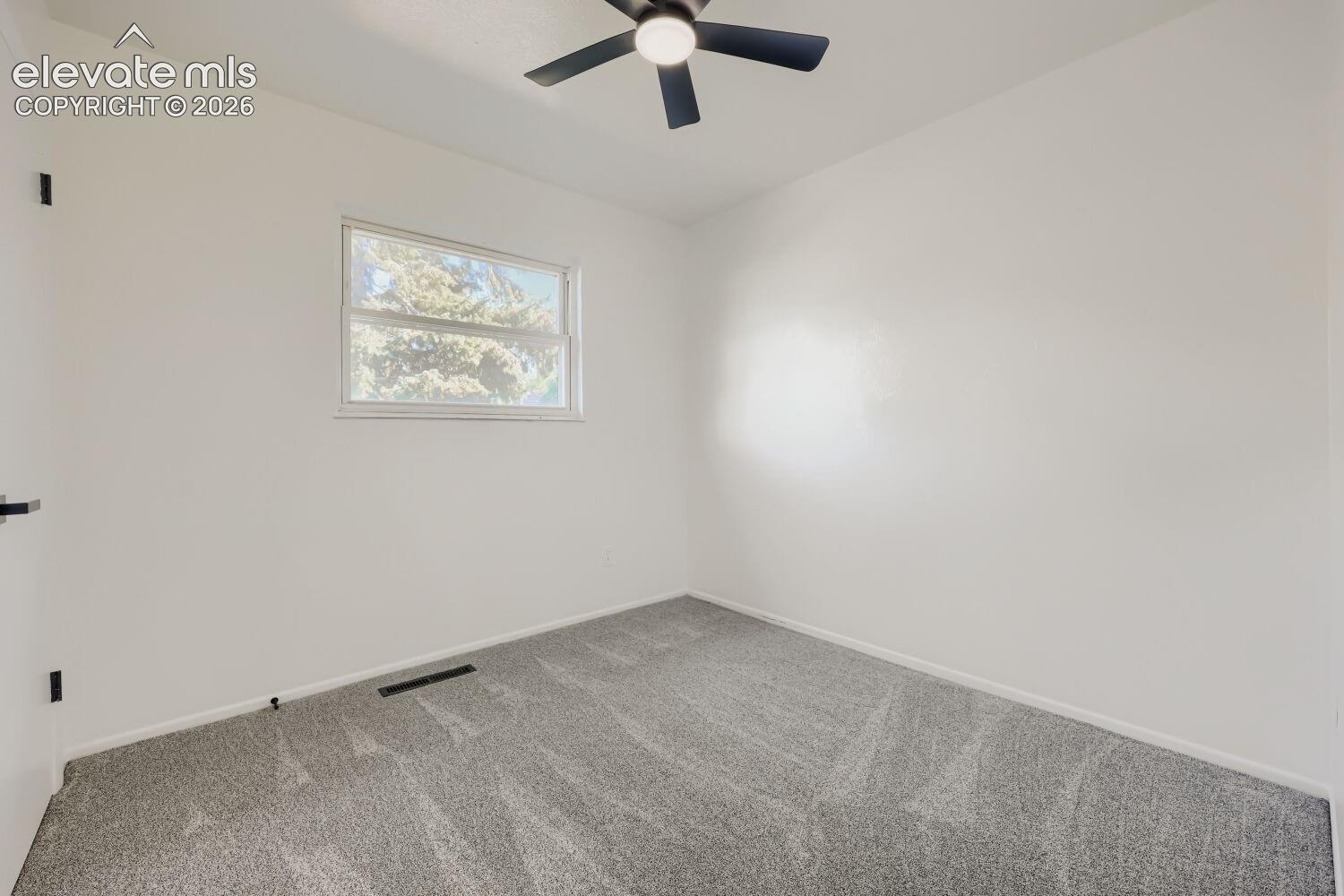 Room with light gray carpeting, white walls, and a black ceiling fan