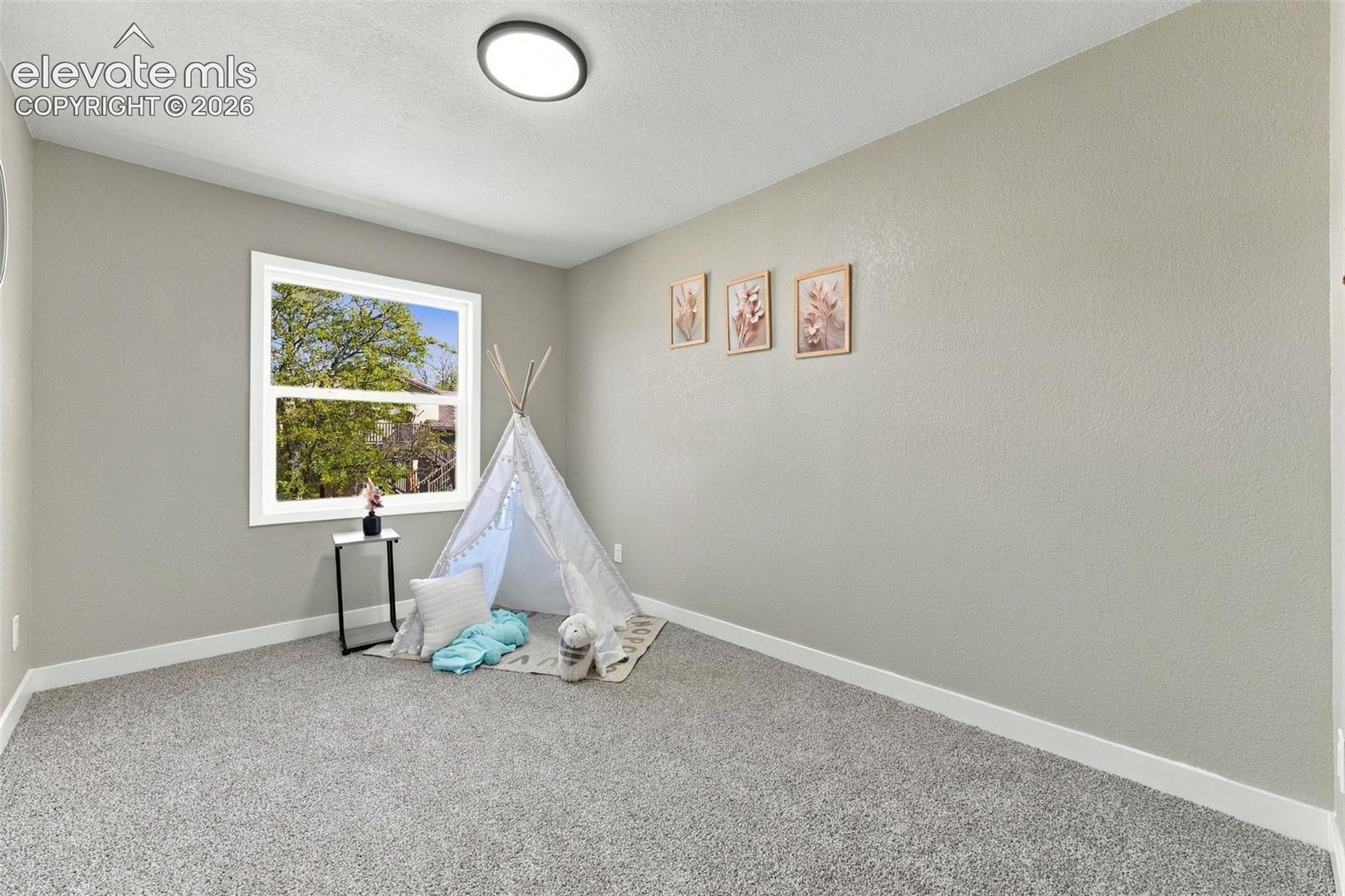 Neutral interior room featuring wall-to-wall carpeting, a single-pane window, and a flush-mount ceiling light fixture