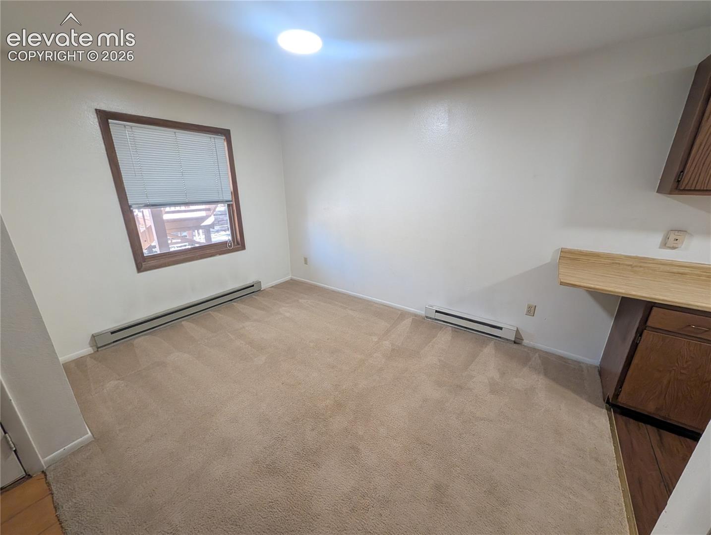 Carpeted flooring, recessed ceiling lighting, a window with wood trim, and baseboard heating units
