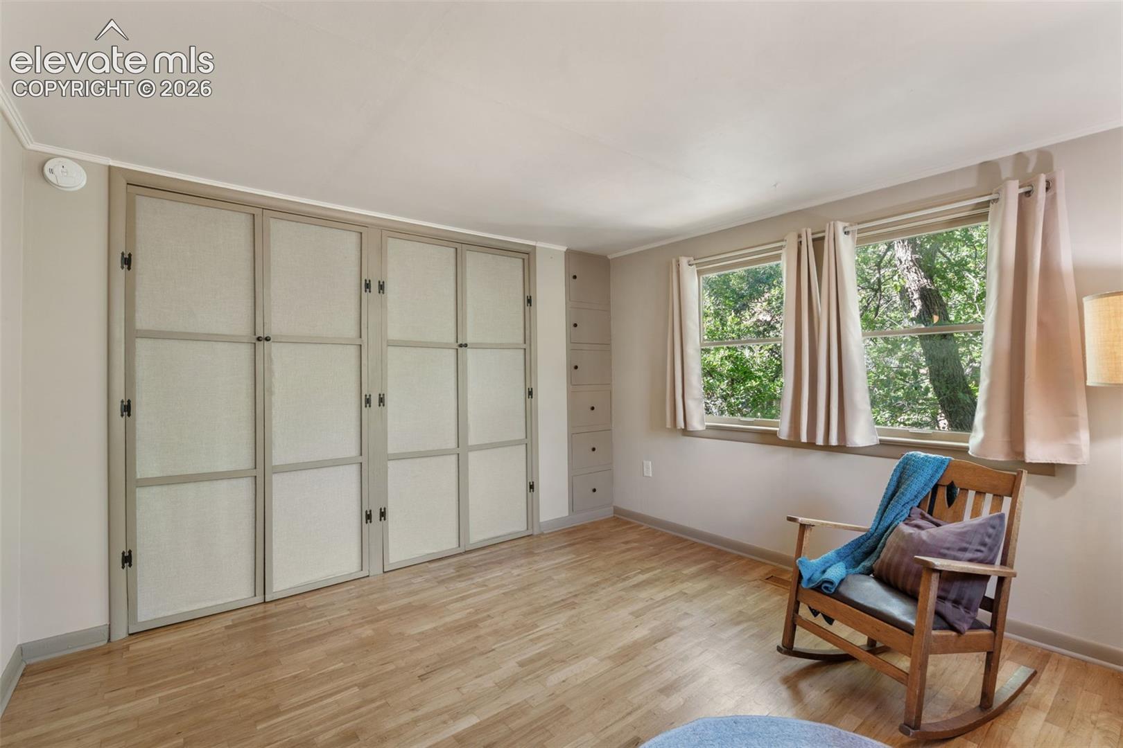 Room featuring wood-finish flooring, two large windows, built-in cabinetry, built-in shelving, and light-toned walls