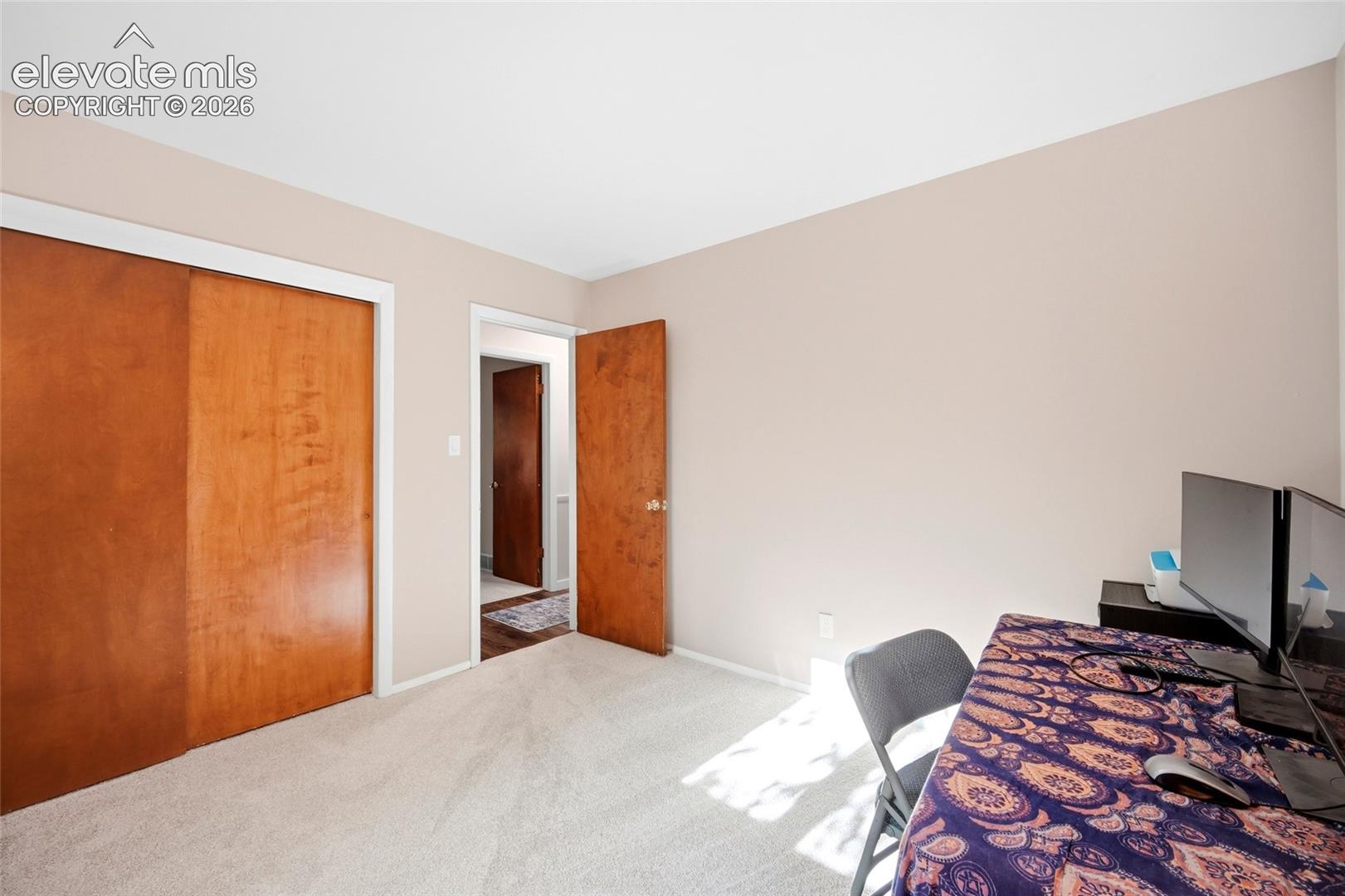 Room featuring neutral wall tones, wall-to-wall carpeting, wood-finish sliding closet doors, and wood-finish interior doors