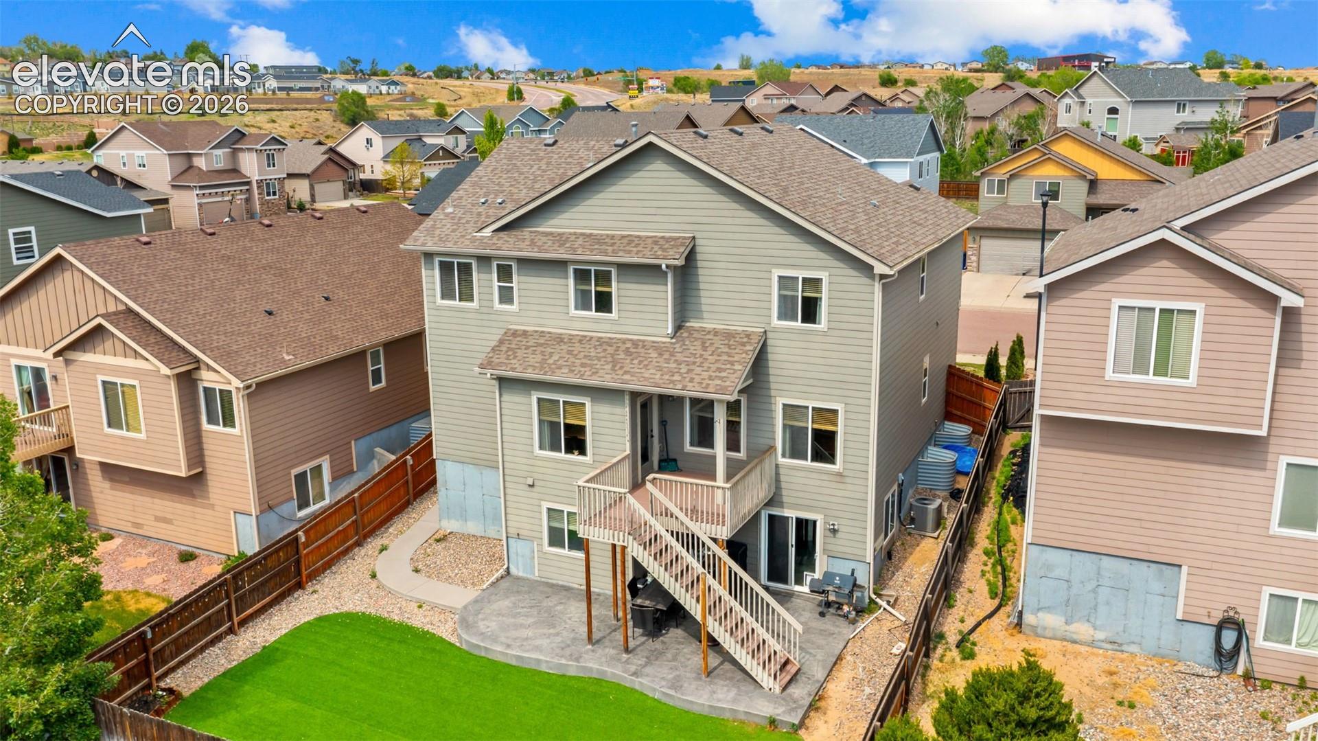 Two-story home featuring a ground-level patio with an upper-level deck, a fenced backyard with artificial turf, and a walk-out basement