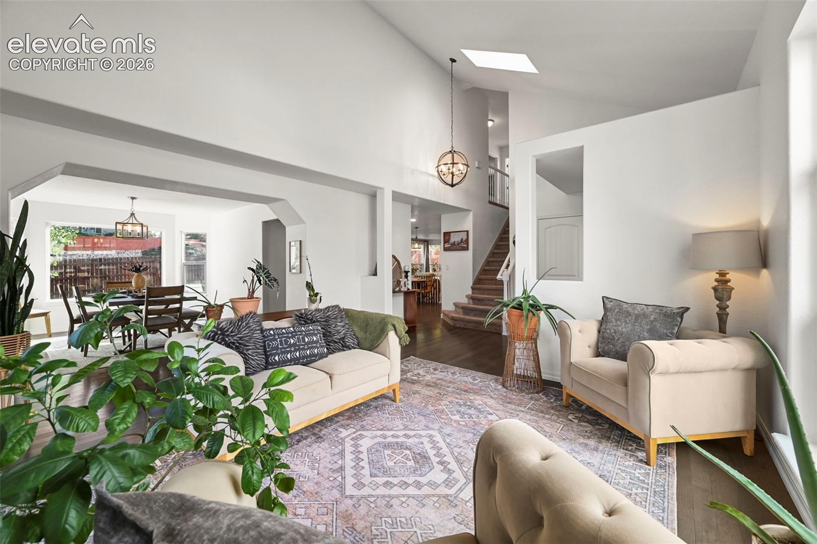 Vaulted ceilings with skylight, wood-finish flooring, recessed lighting, and a chandelier