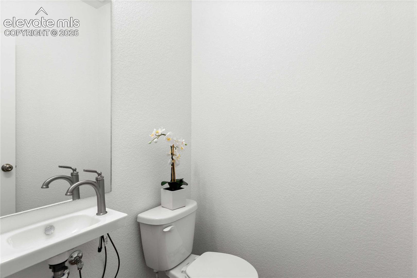 Wall-mounted sink with a modern brushed nickel faucet and a frameless mirror
*photos  of a model home*
