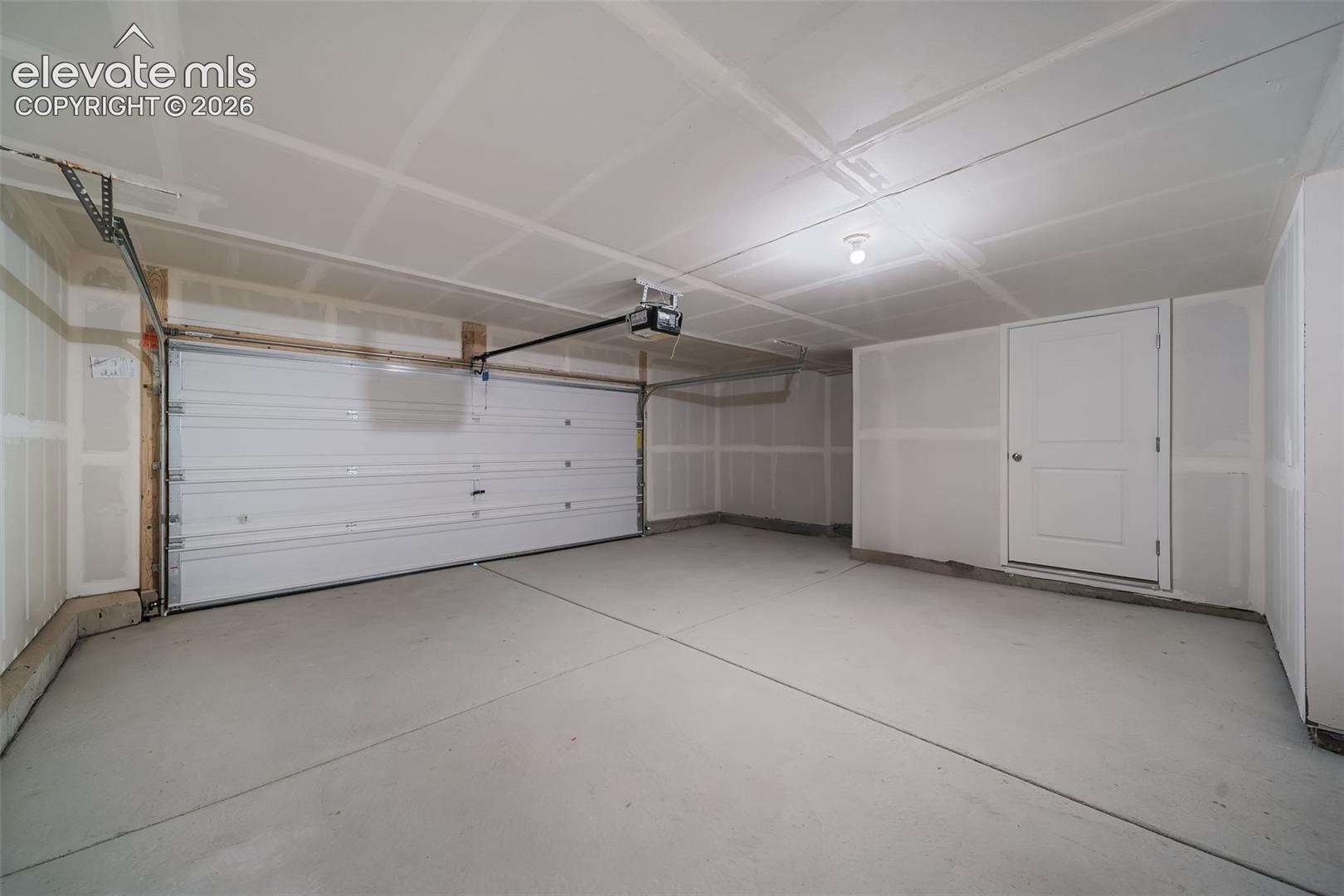 Attached garage featuring a sectional overhead door, concrete flooring, and a single entry door