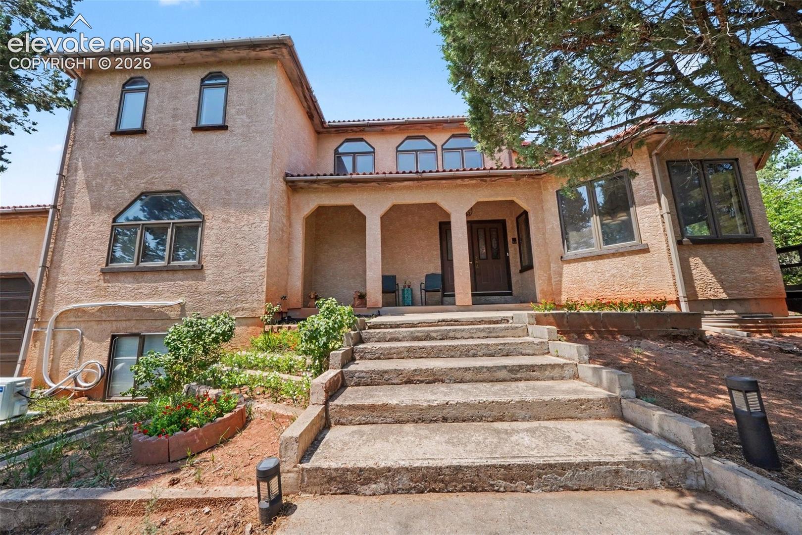 A set of steps leads to the home, surrounded by established landscaping and mature trees that provide privacy and a peaceful, secluded feel