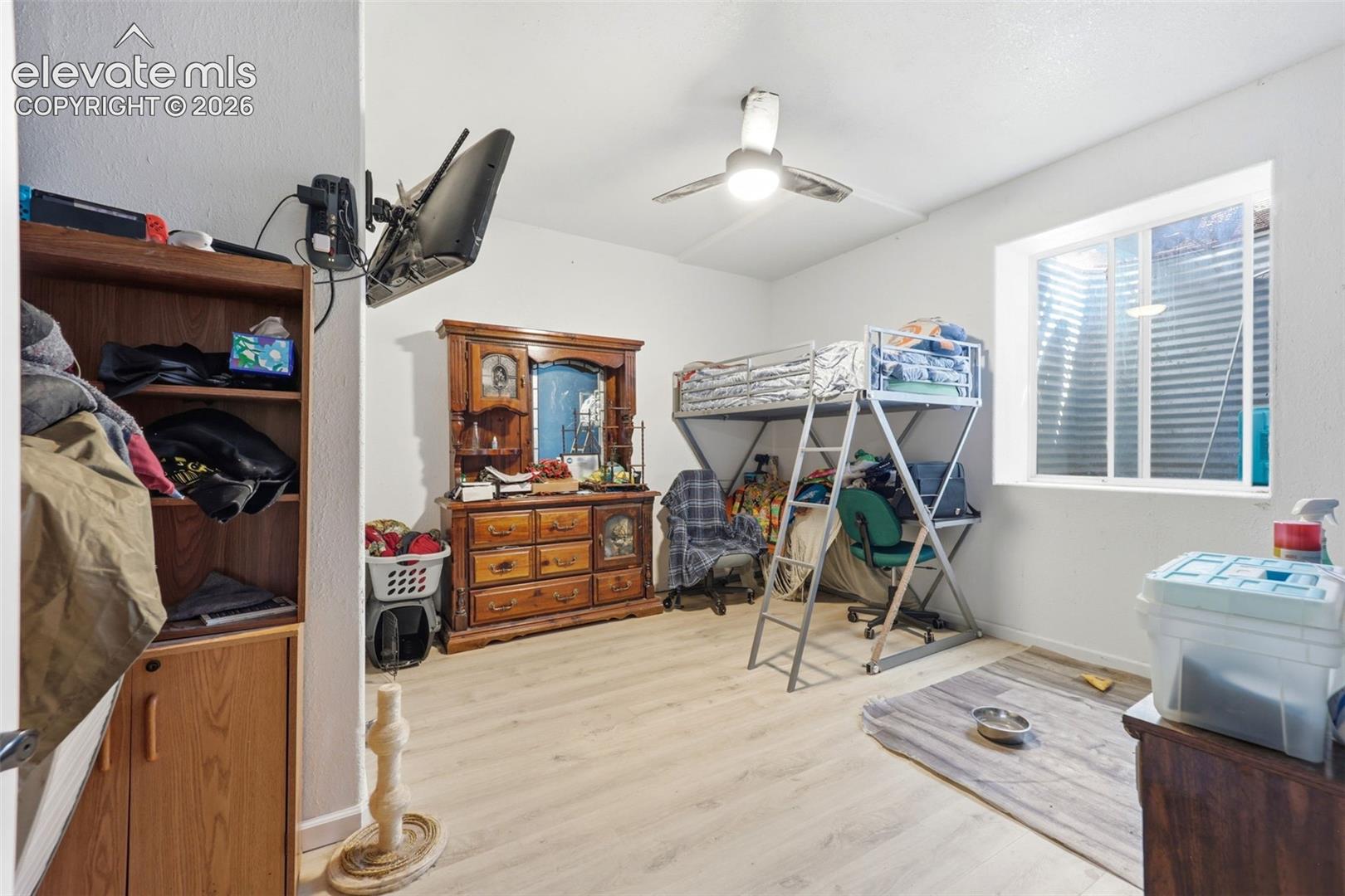Spacious room featuring light wood-finish flooring, a ceiling fan, and a built-in window providing natural illumination