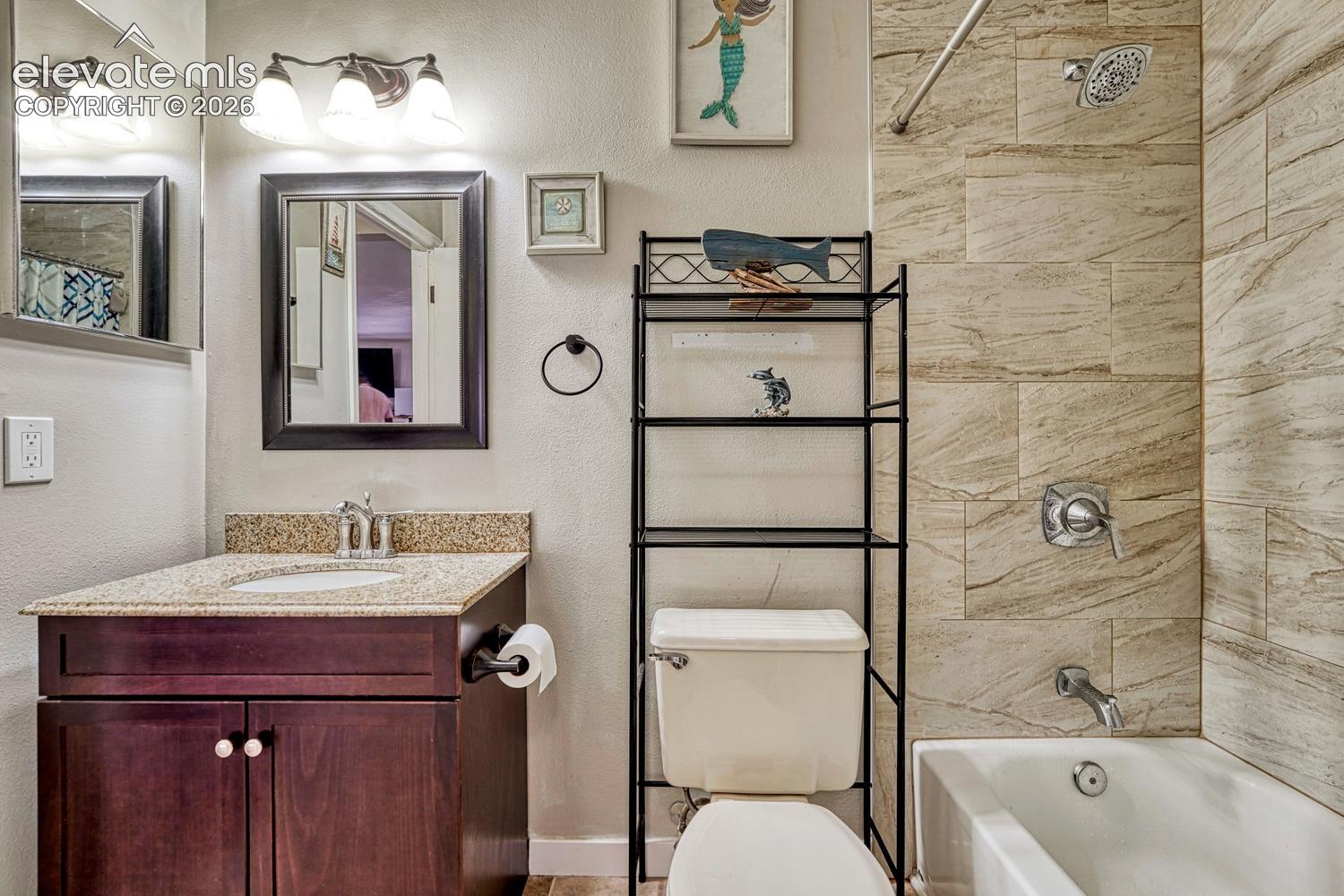 Dark wood-finish vanity with a granite-style countertop and undermount sink