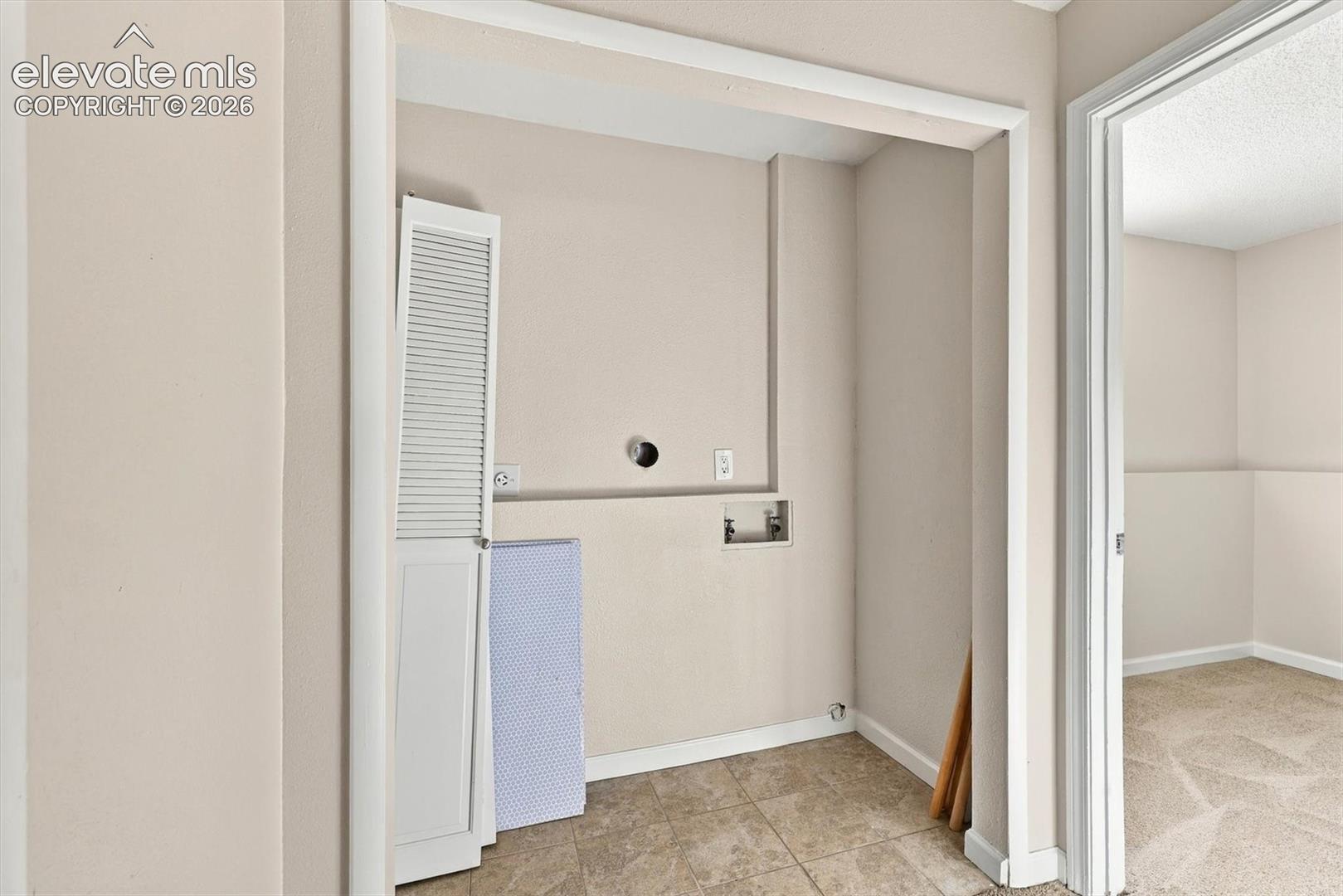 Utility alcove featuring tile flooring and dedicated washer and dryer hookups with integrated water supply and electrical outlets